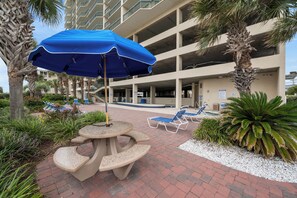 Relax by the pool surrounded by lush greenery and shaded by a picnic table.