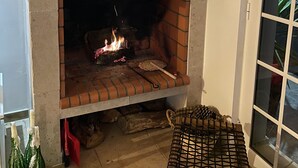 A brick fireplace with a fire, a chair, and two bottles of champagne.