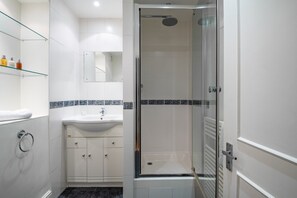 Enjoy a refreshing shower in the bathroom, featuring a glass-enclosed shower with a rain showerhead and a convenient sink with a single faucet.