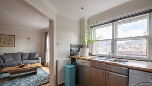 Eine moderne Küche mit Geschirrspüler, Waschmaschine und einem Fenster mit Blick auf Gebäude.