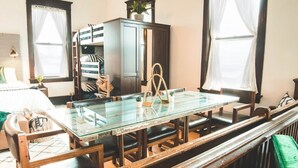 A dining area with a glass-top table, wooden chairs, and benches. - The Courthouse Loft - History with a hot tub!  (El Paso)