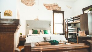 A bedroom with a bed, bunk beds, a wooden headboard, a window, and a brick wall. - The Courthouse Loft - History with a hot tub!  (El Paso)