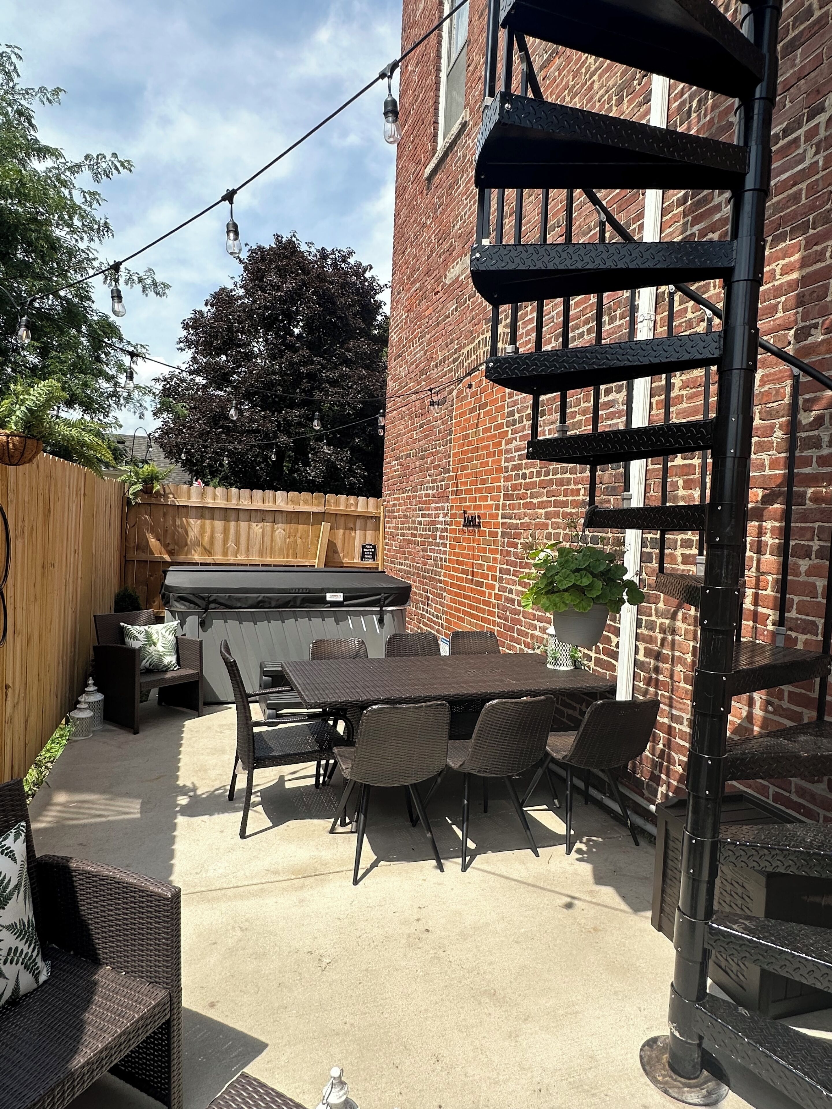 A patio area with a table and chairs, a hot tub, and a brick wall.