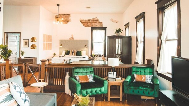 A cozy living room with a green sofa, a wooden coffee table, and a TV. - The Courthouse Loft - History with a hot tub!  (El Paso)