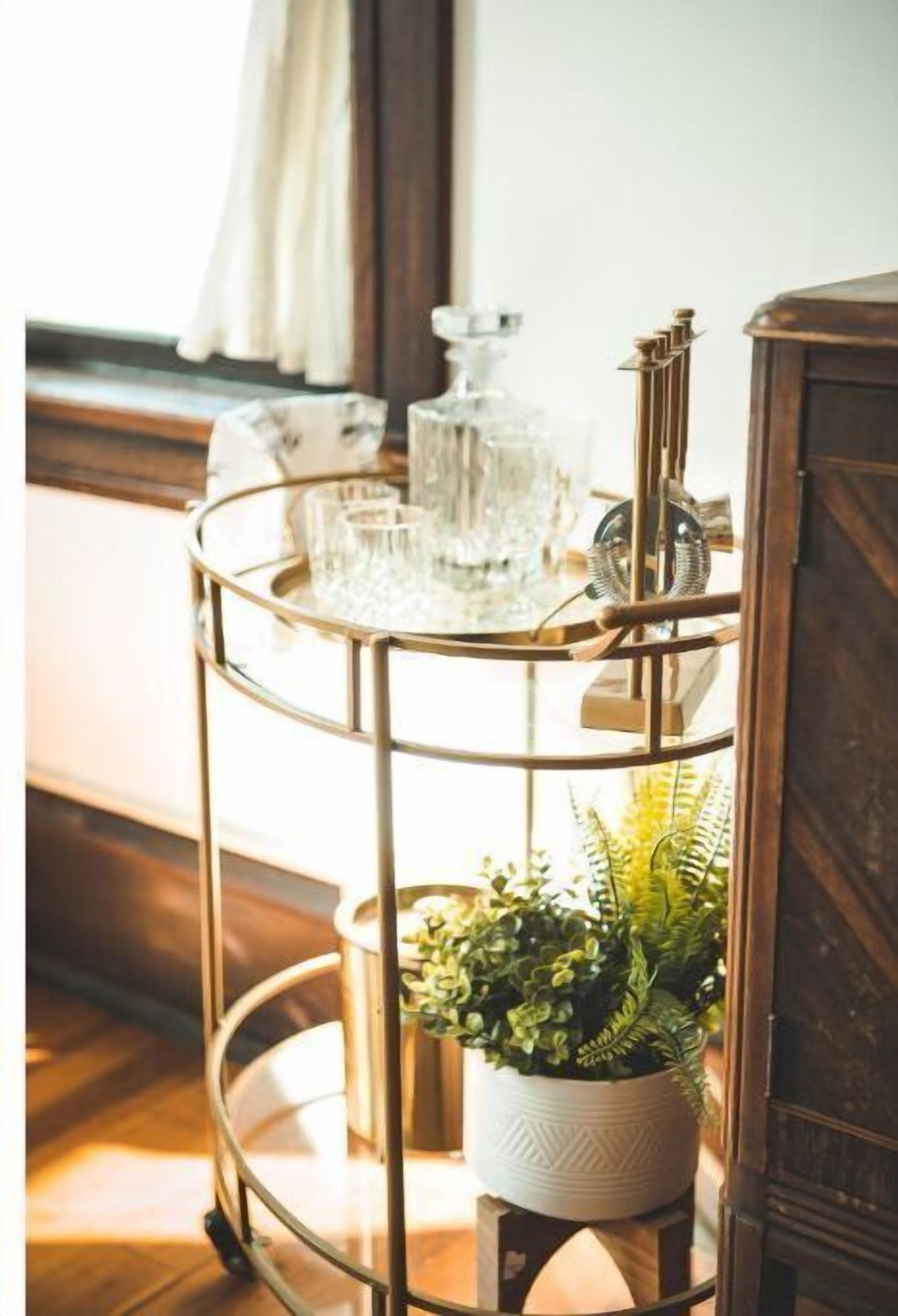 A multi-tiered metal stand with glassware and a potted plant.