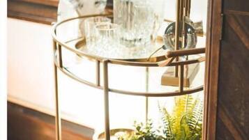 A multi-tiered metal stand with glassware and a potted plant.