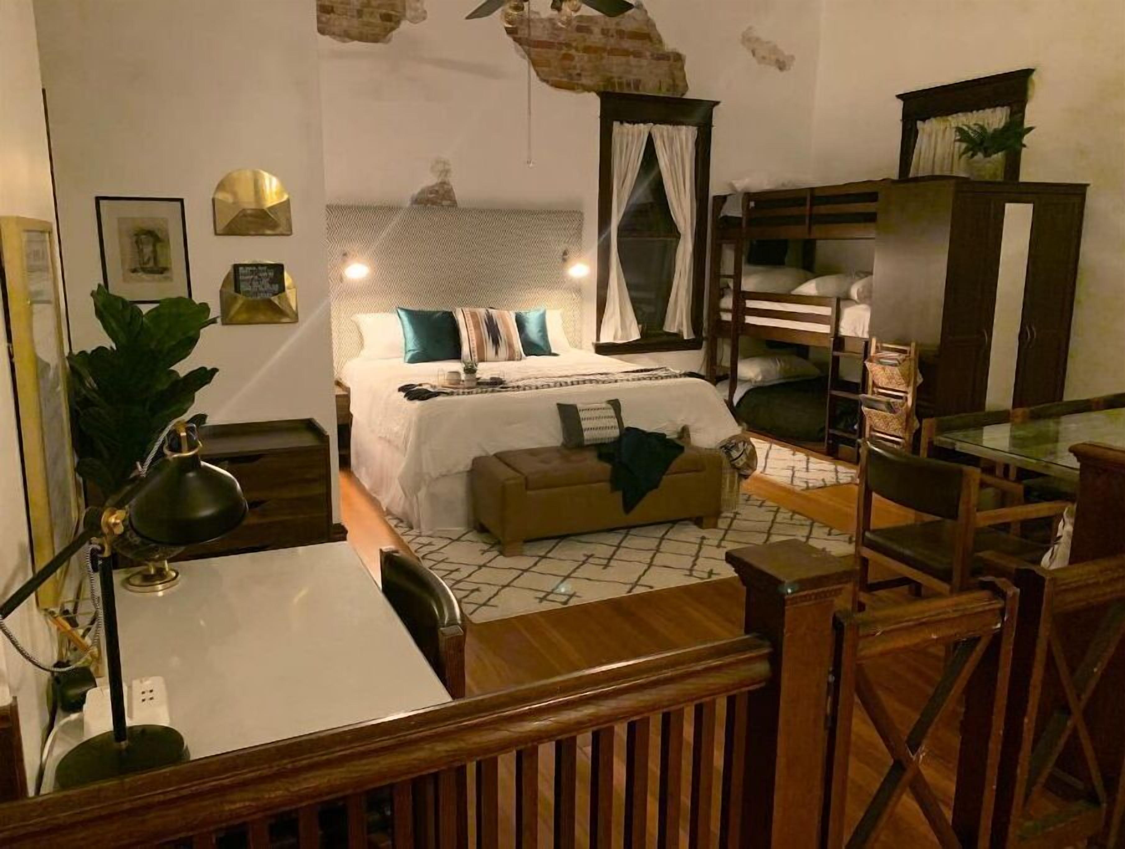 Een gezellige kamer met een bed, een bureau, een stoel, een klein tafeltje en een boekenplank.