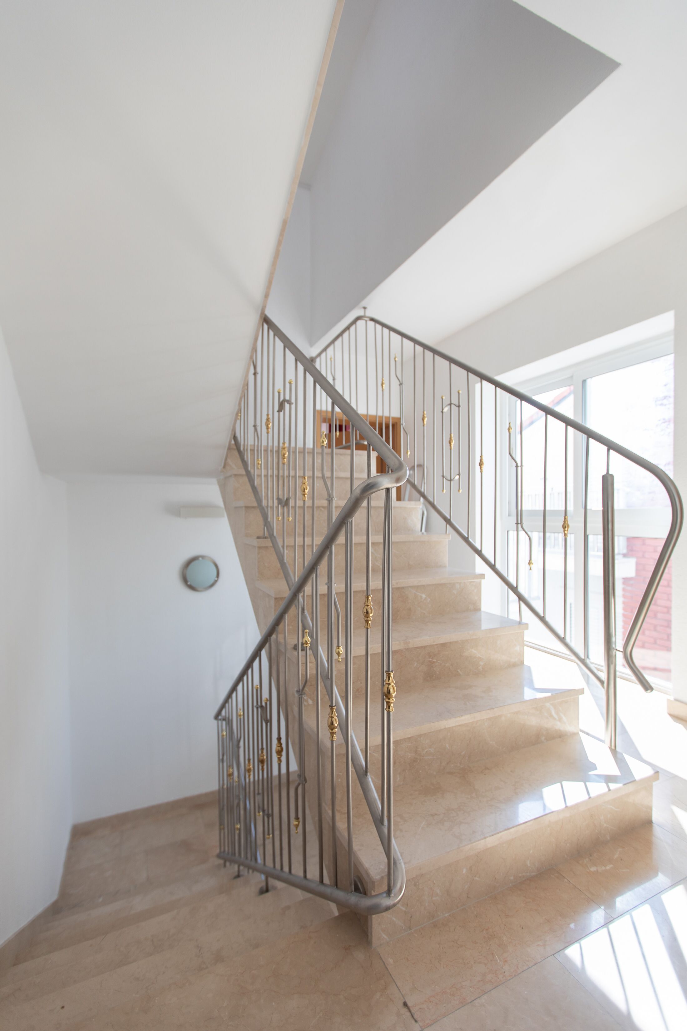 Un escalier moderne avec une rampe en métal et des marches de couleur beige.