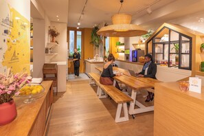 A hotel reception area with wooden benches, a map on the wall, and a reception desk.