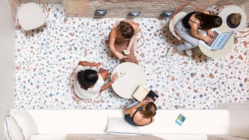 Ein Zimmer mit Terrazzoboden, einem runden Tisch, einer Couch und einem Sessel.