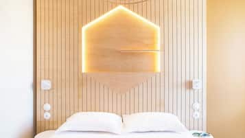 A hotel room with a wooden panel wall, a bed with white bedding, and a unique geometric light fixture above the bed.