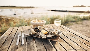 A wooden table with a plate of oysters, a glass of white wine, and a basket of bread. - Vannes, house with swimming pool (Vannes)