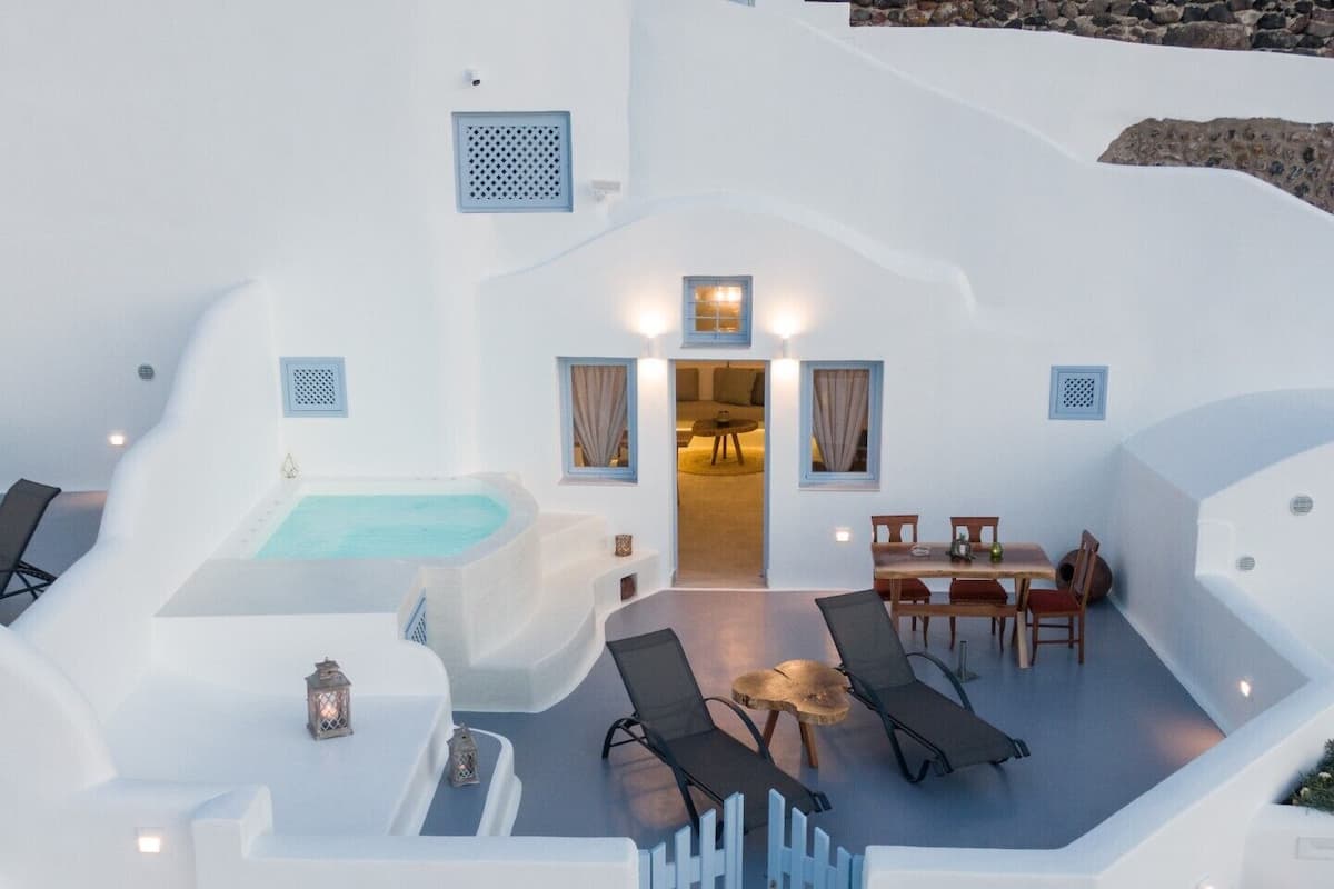 A white villa with a swimming pool, a hot tub, and a dining area with outdoor seating.