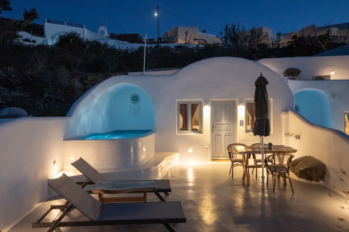 A modern, white-walled building with a pool, a dining area, and a door.