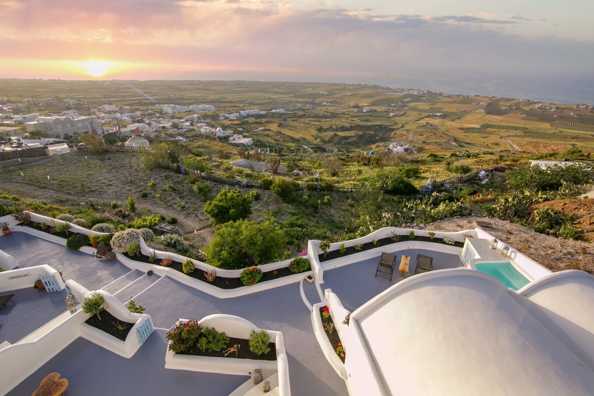A coastal village with white-washed buildings, terraced fields, and a clear view of the sea.