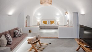 Une chambre à coucher moderne et minimaliste, dotée d’un plafond incurvé, d  ’un lit avec des coussins jaunes, d’une table basse en bois et d’un téléviseur posé sur un meuble en bois.