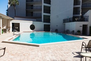 A rectangular swimming pool with a tiled deck, surrounded by lounge chairs and a palm tree. - Anastasia Condos 103- Gorgeous, remodeled condo within walking distance to St. Augustine Beach (St Augustine)