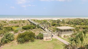 A beach view with a wooden walkway leading to a covered structure.