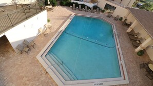 A rectangular pool with a diving board, surrounded by lounge chairs and umbrellas.