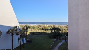 Uitzicht vanaf een balkon op een strand, met een heldere lucht.