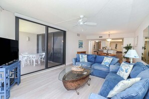 Een moderne woonkamer met een blauwe bank, een glazen salontafel en een tv op een meubel.