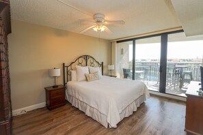 Una camera da letto con un letto grande, due comodini, una ventola a soffitto e vista su un balcone con mobili da esterno.