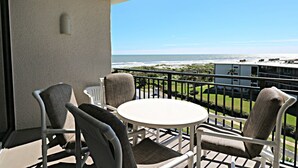 A balcony with a table and chairs, overlooking a beach and ocean. - Miles of Wide Sandy Beaches! Anastasia Condos 603 (St Augustine)