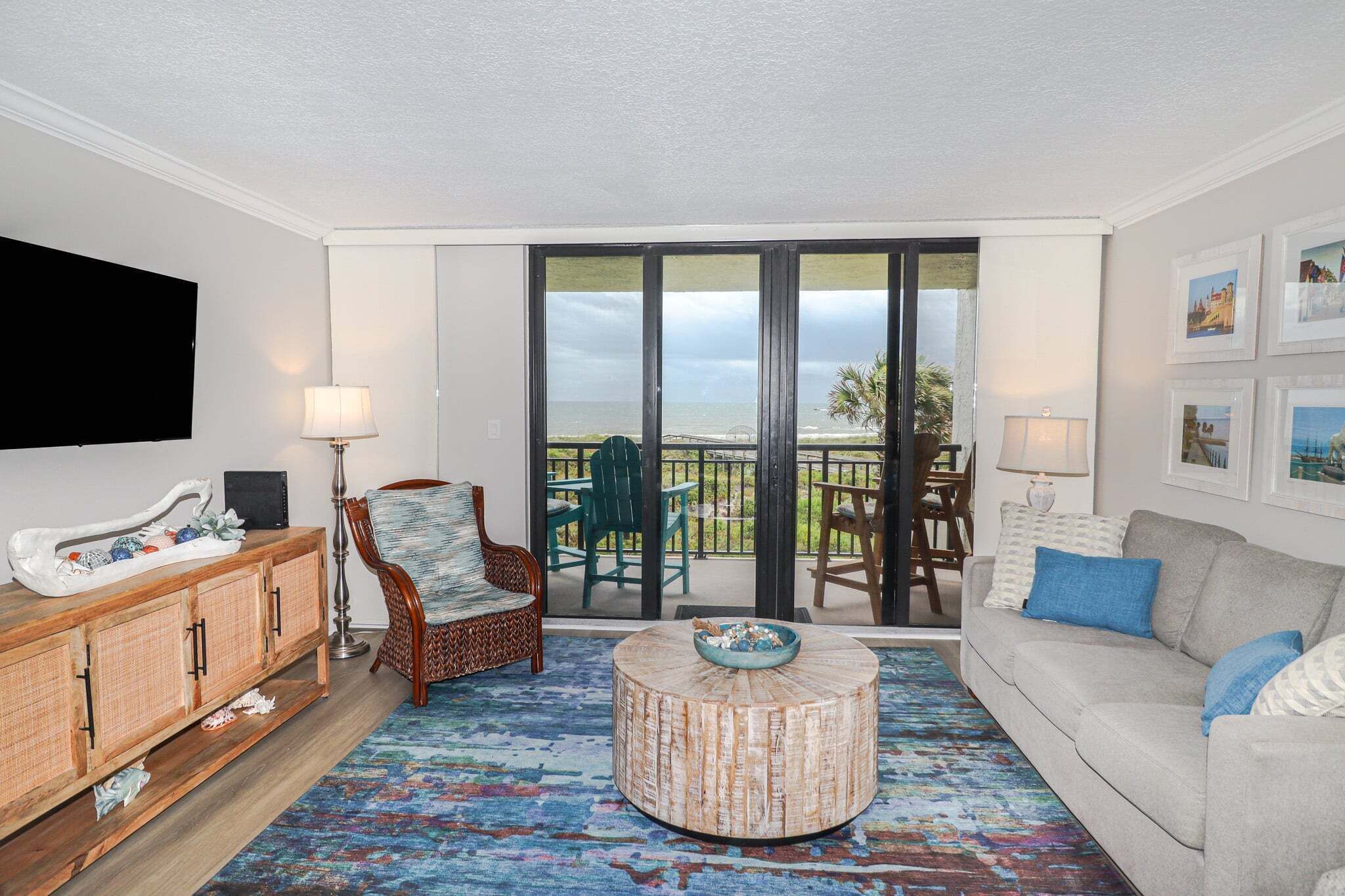 A living room with a sofa, a round coffee table, a wicker chair, a cabinet, and a TV.