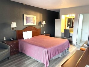 A hotel room with a large bed, bedside lamps, a desk, and a mirror.