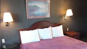 A hotel room with a bed, two bedside lamps, a nightstand, and a framed picture on the wall.