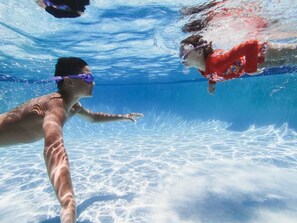 An underwater view of a swimming pool with clear water and visible pool bottom.