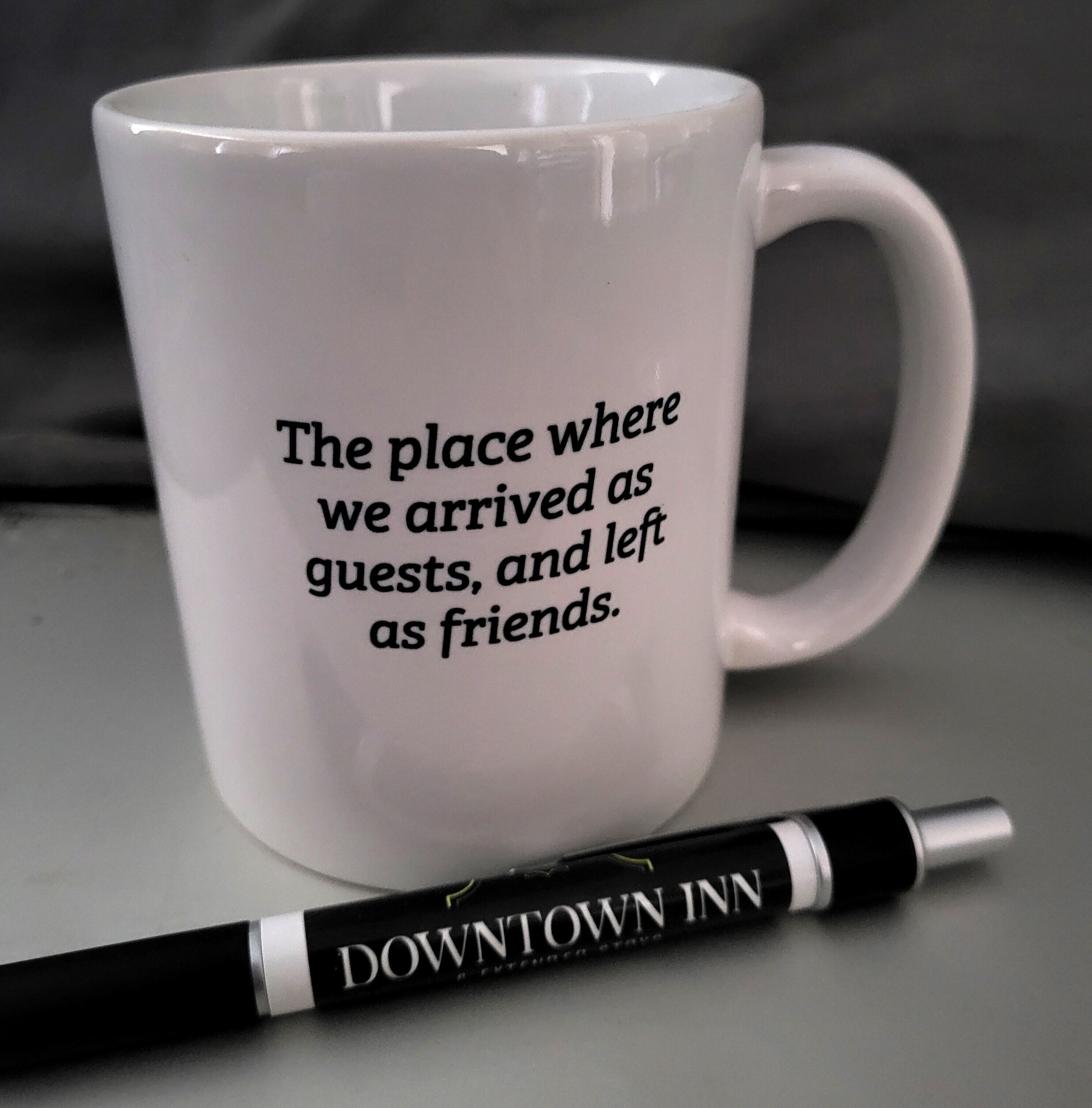A white mug with text and a pen beside it.