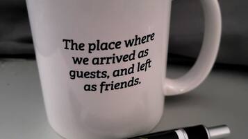 A white mug with text and a pen beside it.