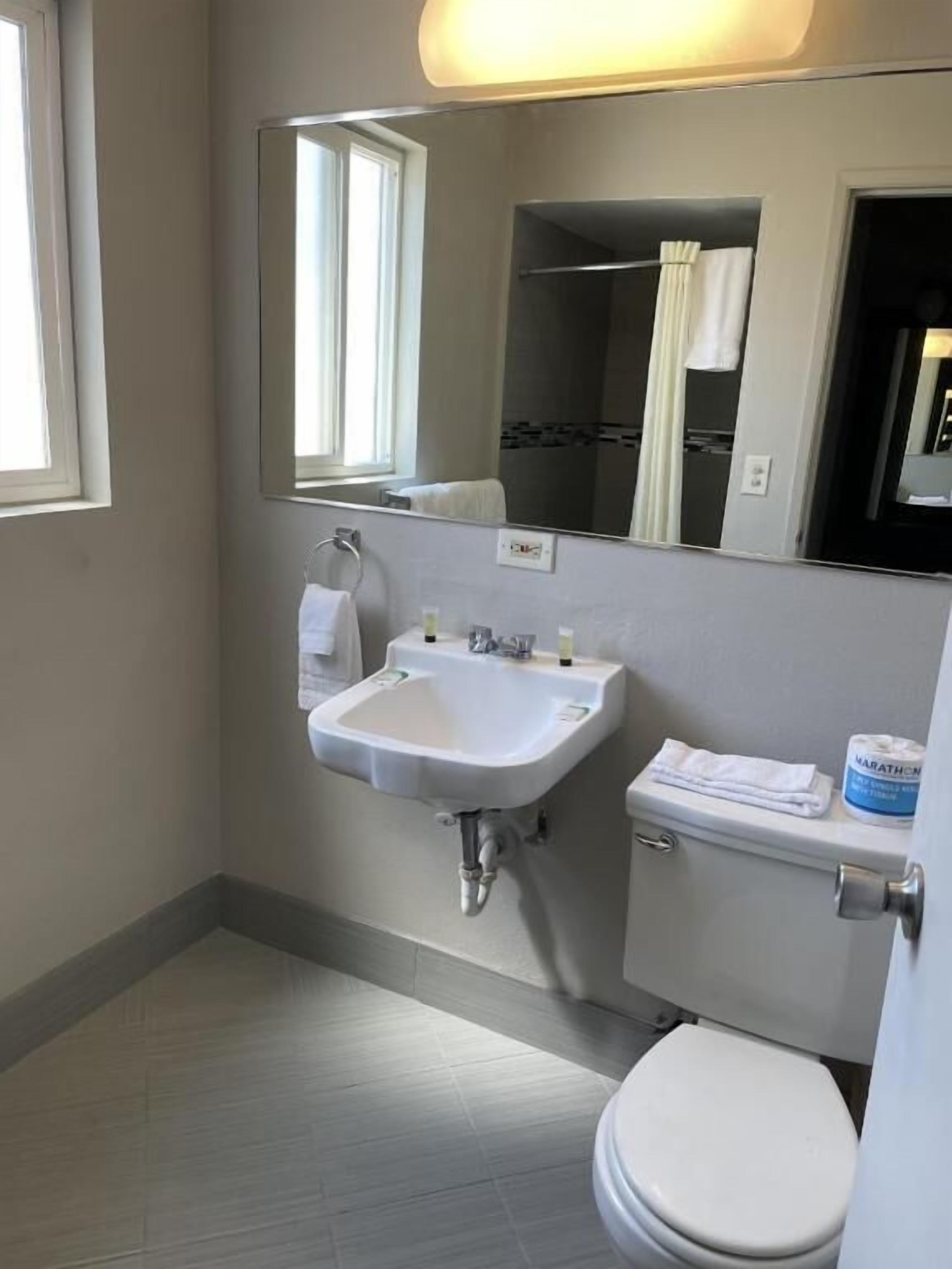 Une salle de bain avec un lavabo blanc, un miroir, des toilettes et un porte-serviettes.