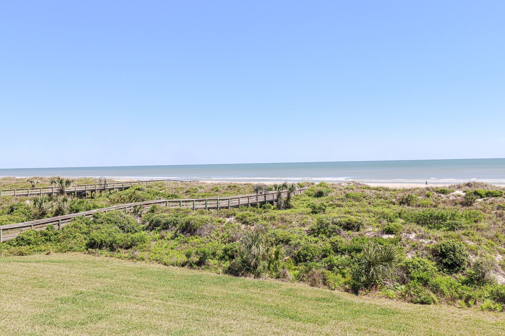 A coastal landscape with a wooden boardwalk leading to the beach.