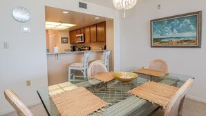 Un comedor con una mesa de vidrio, individuales tejidos y sillas de mimbre.