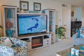 Een woonkamer met een grote flatscreen televisie, een houten entertainmentkast en een open haard.