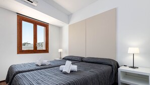 A hotel room with two beds, a large window, a white nightstand, and a wall-mounted shelf. - YourHouse Blaublue 2.3, wonderful sea view apartment in Majorca North (Can Picafort)