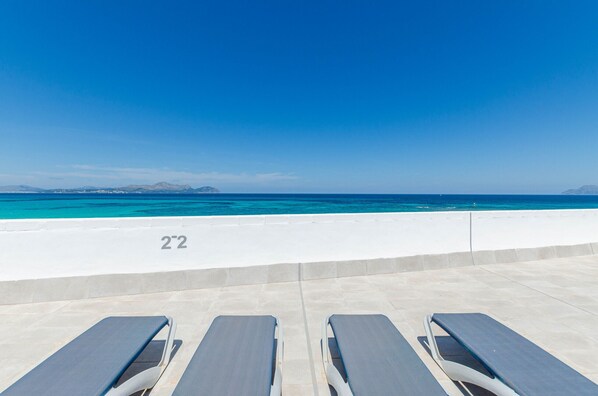 A poolside area with lounge chairs and a clear view of the ocean. - YourHouse Blaublue 2.3, wonderful sea view apartment in Majorca North (Can Picafort)