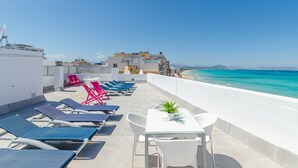 A rooftop terrace with lounge chairs, a table, and a view of the sea. - YourHouse Blaublue 2.3, wonderful sea view apartment in Majorca North (Can Picafort)
