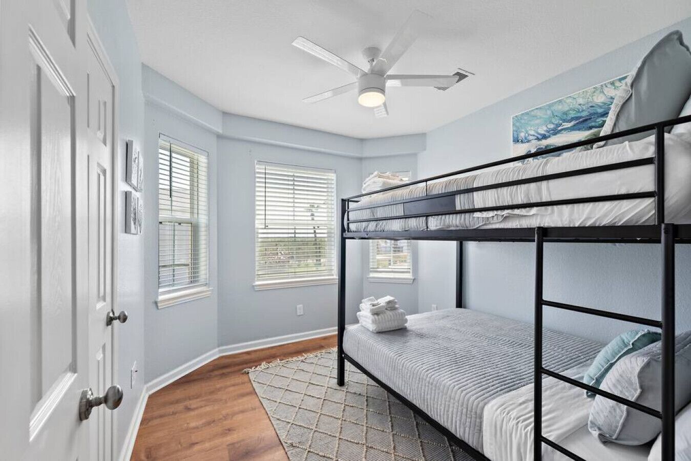 A room with a bunk bed, a ceiling fan, and a window with blinds.