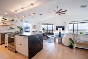 Une cuisine moderne dotée d’un îlot en marbre, d’un four encastré et de luminaires suspendus.