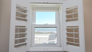 Habitación de esquina con ventana que da a la playa y un edificio.