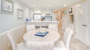 Un coin repas avec une table ronde, des chaises en osier blanc et un saladier posé sur un set de table.