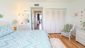 Un dormitorio con cama, una silla, un aparador y un armario.