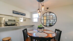 A modern kitchen with stainless steel appliances, a dining area with a round table and black chairs, and a large mirror on the wall. - Enjoy this one bedroom condo overlooking the pool, Creston House 5A (St. Augustine)
