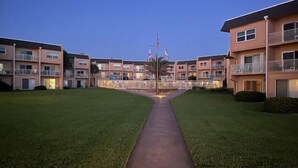 A multi-story residential building with a central pathway leading to a flagpole. - Enjoy this one bedroom condo overlooking the pool, Creston House 5A (St. Augustine)