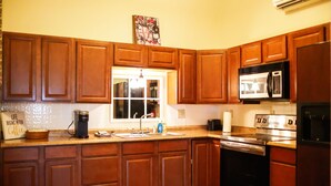 A kitchen with wooden cabinets, a microwave, a coffee maker, and a window.