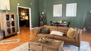 A living room with a brown leather sofa, a wooden coffee table, and a dining area with a table and chairs.