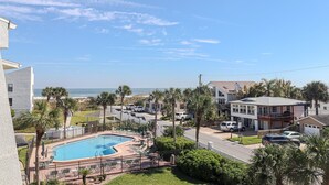 A residential area with a swimming pool, palm trees, and a view of the ocean. - Island South 33 Ocean View Condo On Third Floor (St. Augustine)